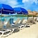 A series of lounge chairs and beach umbrellas lined up a sandy shore